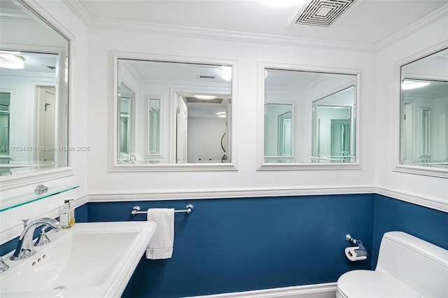 half bath featuring ornamental molding, visible vents, a sink, and toilet