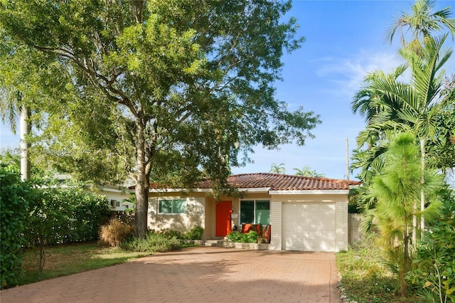 view of front of property featuring a garage, a tile roof, and decorative driveway