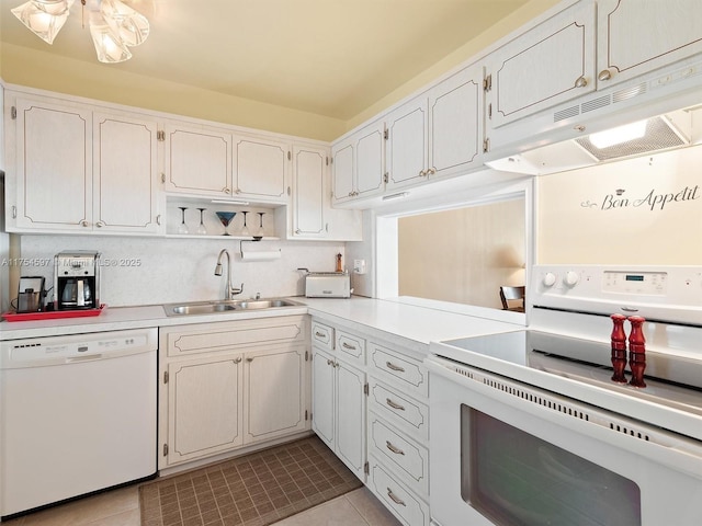 kitchen with light tile patterned floors, under cabinet range hood, white appliances, a sink, and light countertops