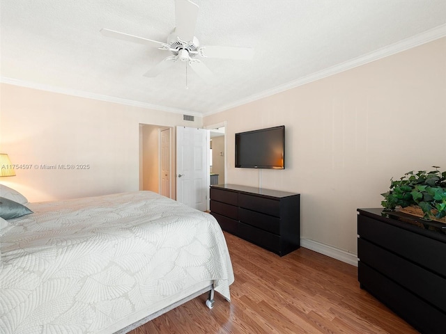 bedroom with crown molding, visible vents, and wood finished floors