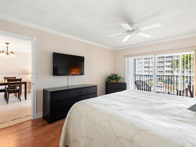 bedroom with ornamental molding, access to exterior, a textured ceiling, and wood finished floors