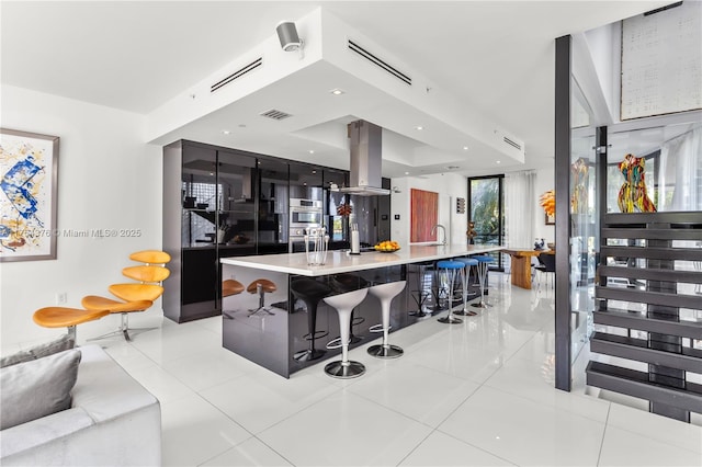 kitchen with light tile patterned floors, double oven, a sink, visible vents, and island exhaust hood