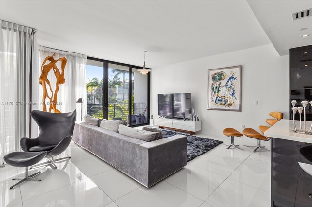 tiled living area featuring french doors, a wall of windows, and visible vents