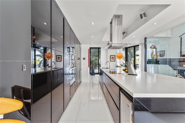 kitchen with light tile patterned floors, recessed lighting, light countertops, island range hood, and modern cabinets