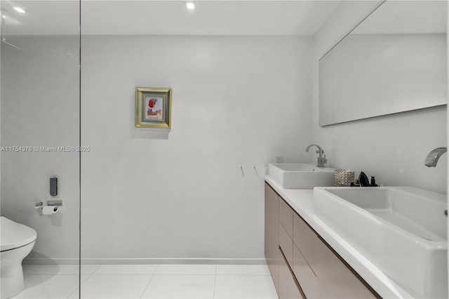 bathroom featuring double vanity, tile patterned flooring, a sink, and toilet