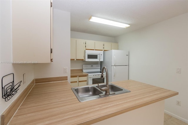 kitchen with white appliances, baseboards, light countertops, a textured ceiling, and a sink