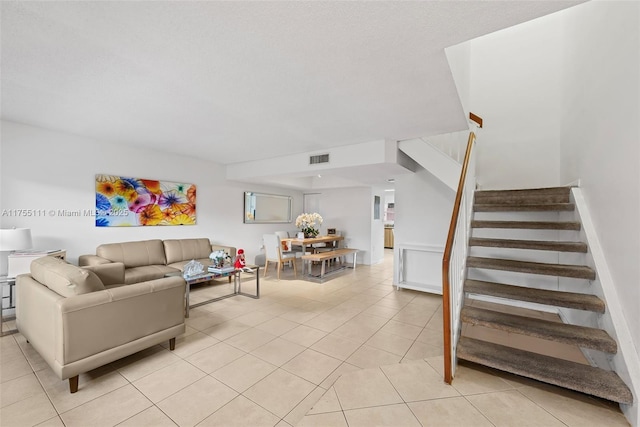 living room featuring stairs, light tile patterned flooring, and visible vents