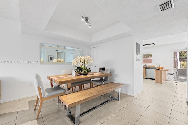 dining area featuring a textured ceiling, light tile patterned flooring, a raised ceiling, and visible vents