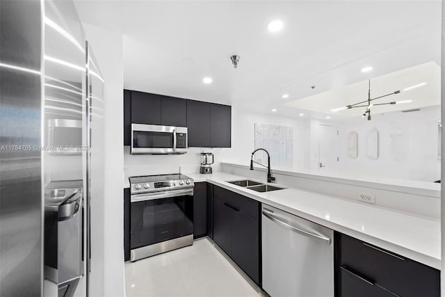 kitchen with light countertops, appliances with stainless steel finishes, a sink, modern cabinets, and dark cabinetry