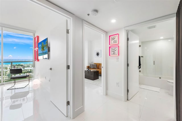 hall featuring a water view, light tile patterned floors, baseboards, and visible vents