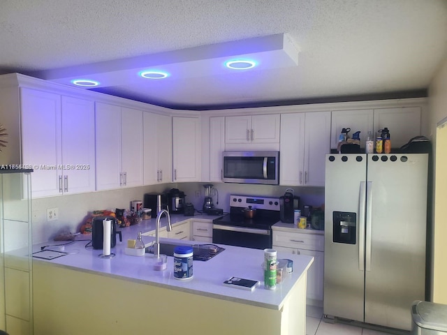 kitchen with a sink, white cabinetry, appliances with stainless steel finishes, a peninsula, and light countertops