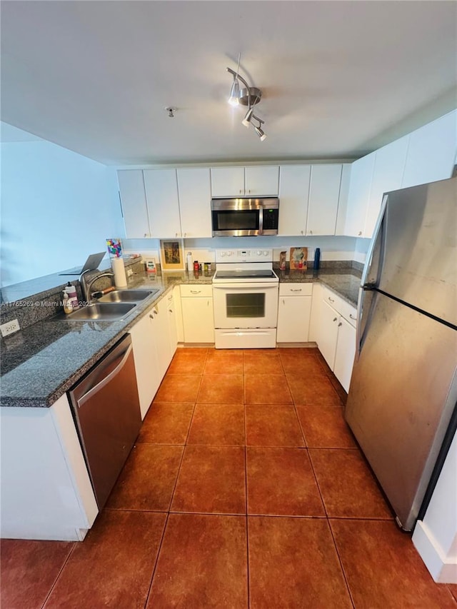 kitchen featuring dark countertops, appliances with stainless steel finishes, a sink, and dark tile patterned flooring