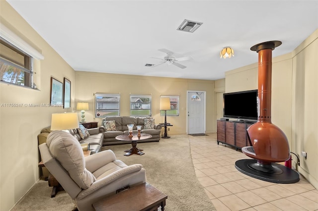 living area featuring light tile patterned flooring, ceiling fan, visible vents, and light colored carpet