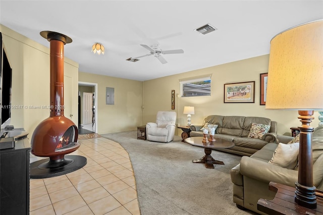 living room with light tile patterned floors, light colored carpet, visible vents, ceiling fan, and electric panel