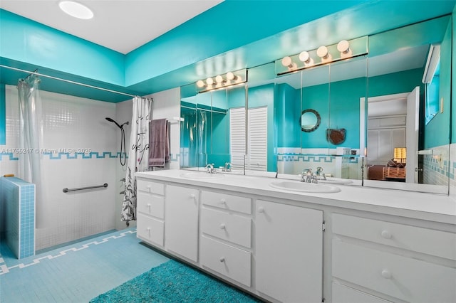 full bathroom with double vanity, tiled shower, and a sink