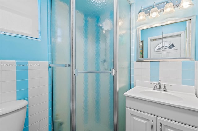 full bathroom featuring toilet, tile walls, a shower stall, and vanity