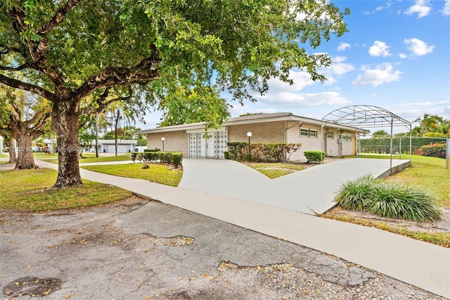 view of front of home with fence, a front lawn, concrete driveway, and brick siding