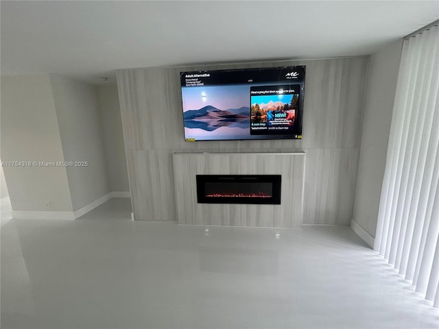 room details with finished concrete flooring, a glass covered fireplace, and baseboards