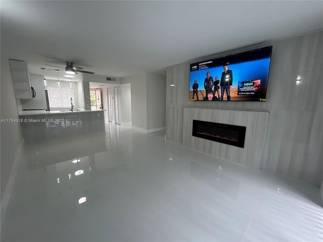 unfurnished living room featuring a fireplace, a sink, visible vents, and ceiling fan