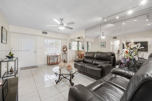 living area with a textured ceiling, ceiling fan, light tile patterned floors, and visible vents