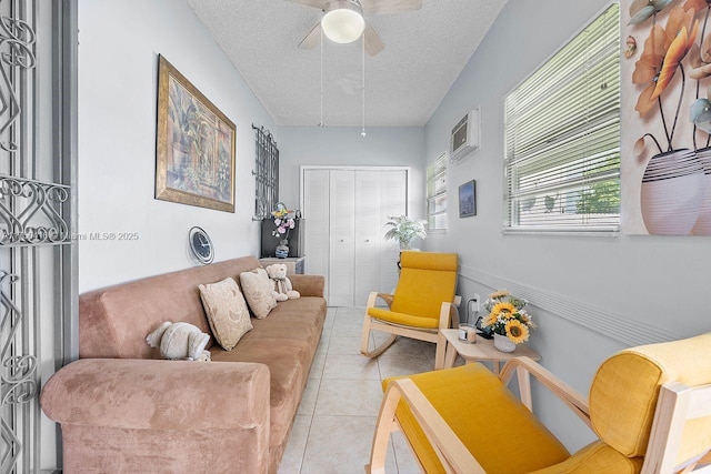 living room featuring ceiling fan, a wall mounted air conditioner, a textured ceiling, and light tile patterned flooring