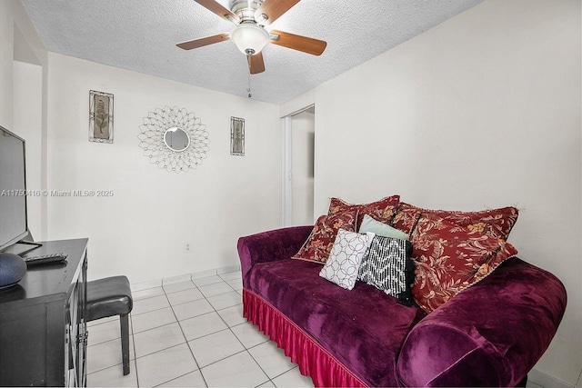 living area with light tile patterned floors, a ceiling fan, and a textured ceiling