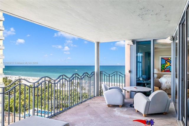 balcony with a water view and a view of the beach