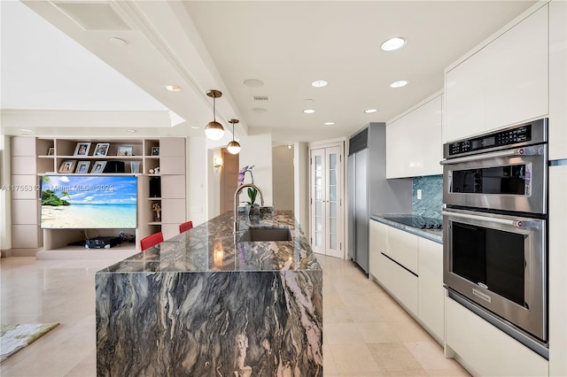 kitchen with black electric stovetop, stainless steel double oven, white cabinets, a sink, and modern cabinets