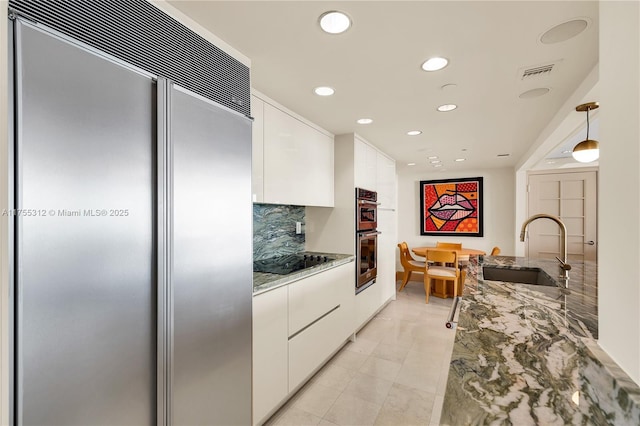 kitchen with light stone counters, stainless steel appliances, white cabinets, a sink, and modern cabinets