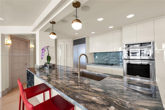 kitchen featuring built in fridge, visible vents, backsplash, stainless steel double oven, and a sink