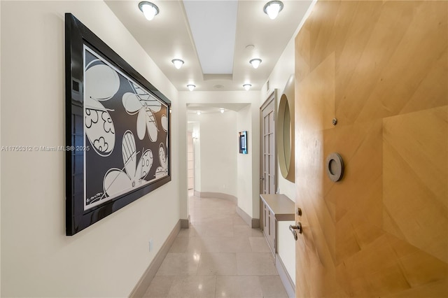 corridor featuring baseboards and light tile patterned floors