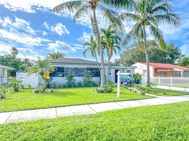 view of front facade with a front yard, fence, and stucco siding