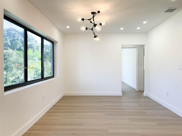 unfurnished room with recessed lighting, visible vents, light wood-style flooring, an inviting chandelier, and baseboards