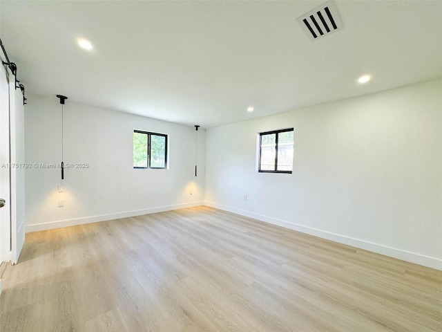 spare room featuring plenty of natural light, visible vents, and baseboards