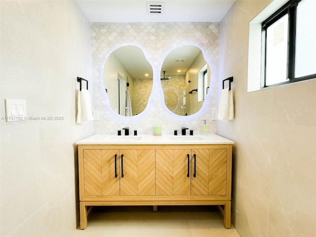 full bath with a sink, visible vents, and tile walls