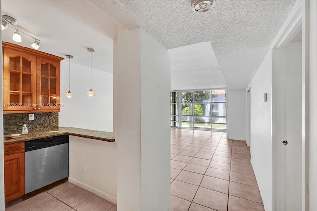 kitchen with light tile patterned floors, brown cabinets, glass insert cabinets, stainless steel dishwasher, and tasteful backsplash