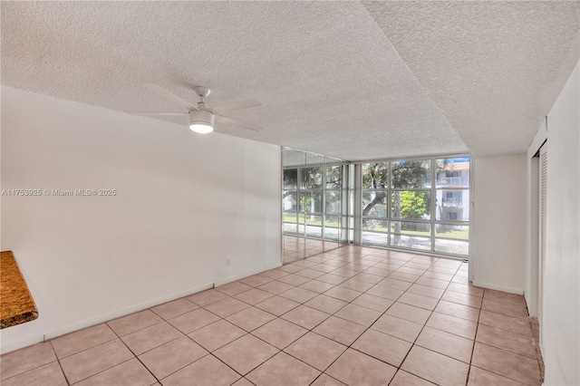 spare room with ceiling fan, a textured ceiling, light tile patterned floors, and expansive windows