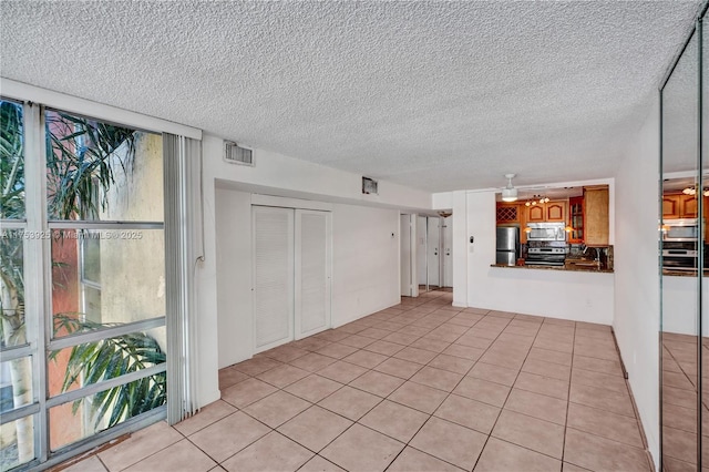 interior space featuring light tile patterned floors, visible vents, and a textured ceiling