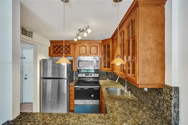 kitchen with visible vents, glass insert cabinets, dark stone counters, stainless steel appliances, and a sink