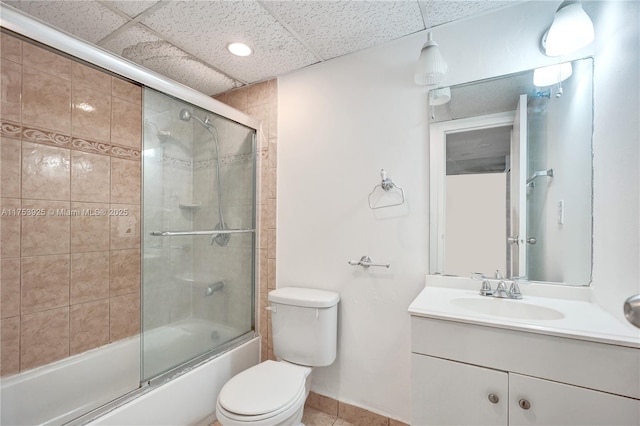 full bathroom featuring baseboards, a drop ceiling, toilet, enclosed tub / shower combo, and vanity