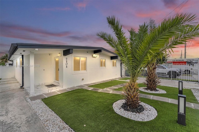 view of front of house with a yard, fence, and stucco siding