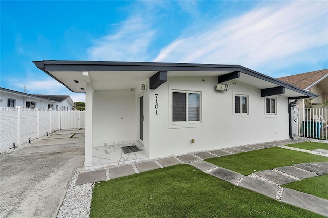 view of front facade featuring a front lawn, a patio area, fence, and stucco siding