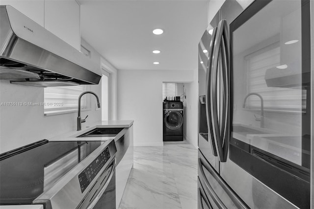 kitchen with modern cabinets, appliances with stainless steel finishes, washer / clothes dryer, range hood, and a sink