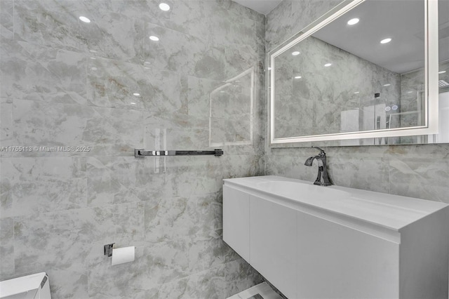 bathroom with vanity, walk in shower, tile walls, and recessed lighting