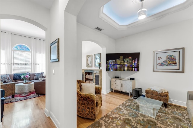 interior space featuring light wood finished floors, baseboards, visible vents, and arched walkways