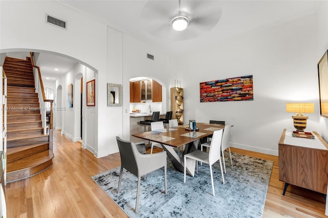 dining area featuring arched walkways, visible vents, and light wood-style floors