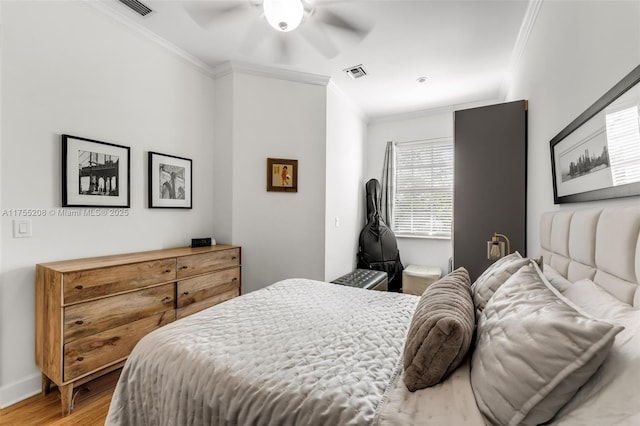 bedroom with visible vents, crown molding, baseboards, and wood finished floors