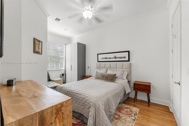 bedroom featuring baseboards, visible vents, ceiling fan, crown molding, and light wood-style floors