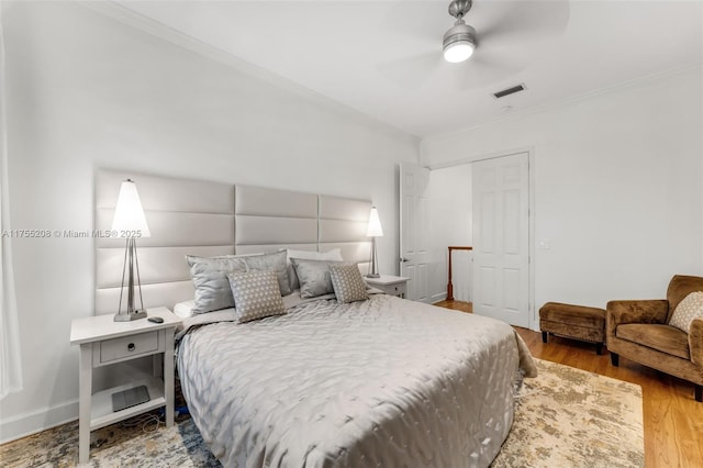 bedroom featuring crown molding, visible vents, ceiling fan, wood finished floors, and baseboards