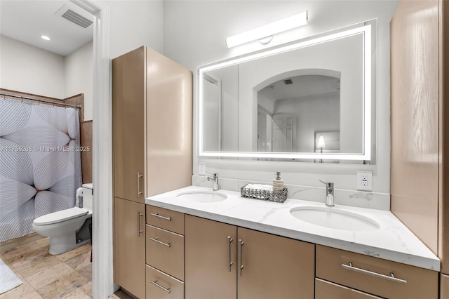 full bathroom with visible vents, a sink, toilet, and double vanity